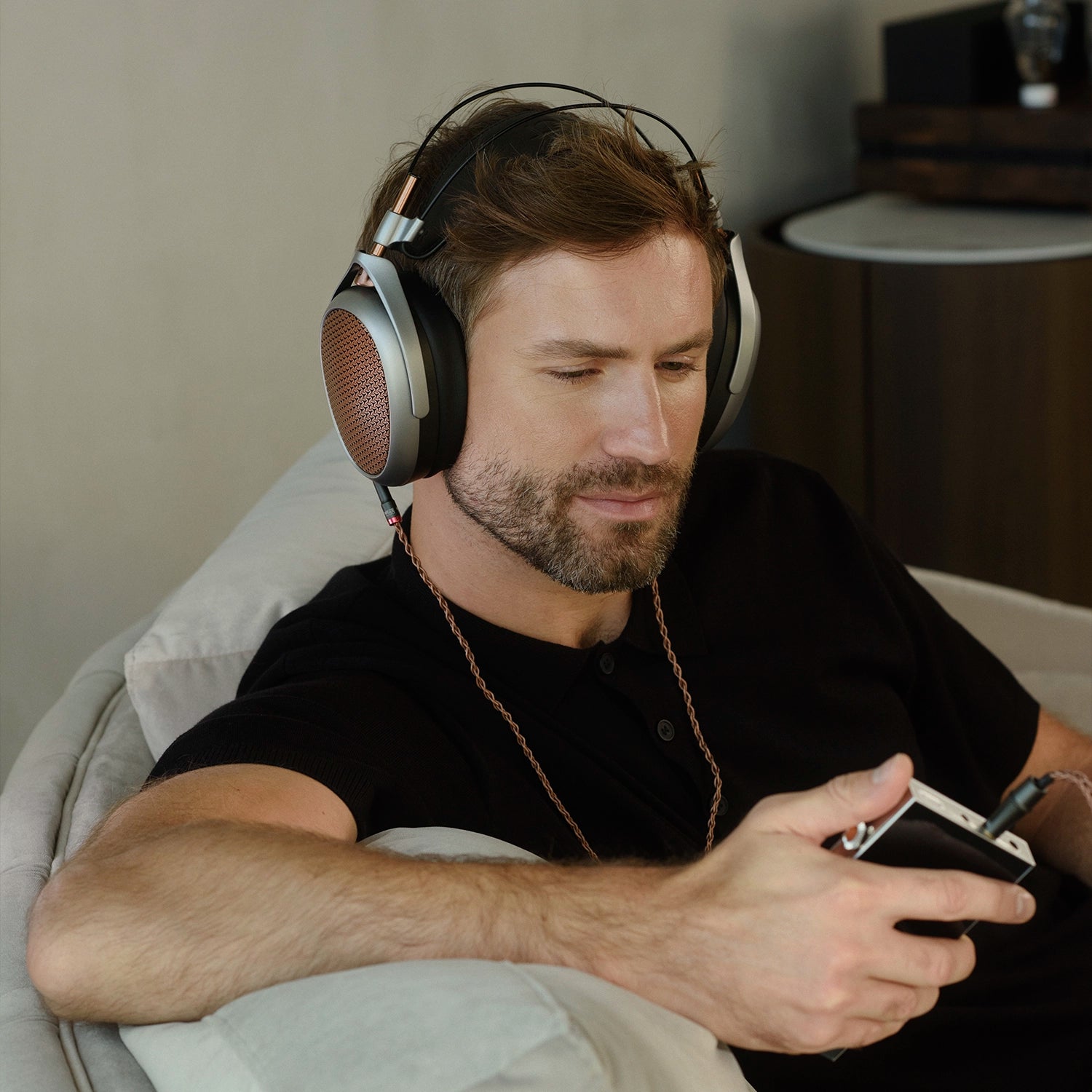 Man listening to Meze Audio POET premium build open-back planar magnetic driver copper ear cups copper cable indoors