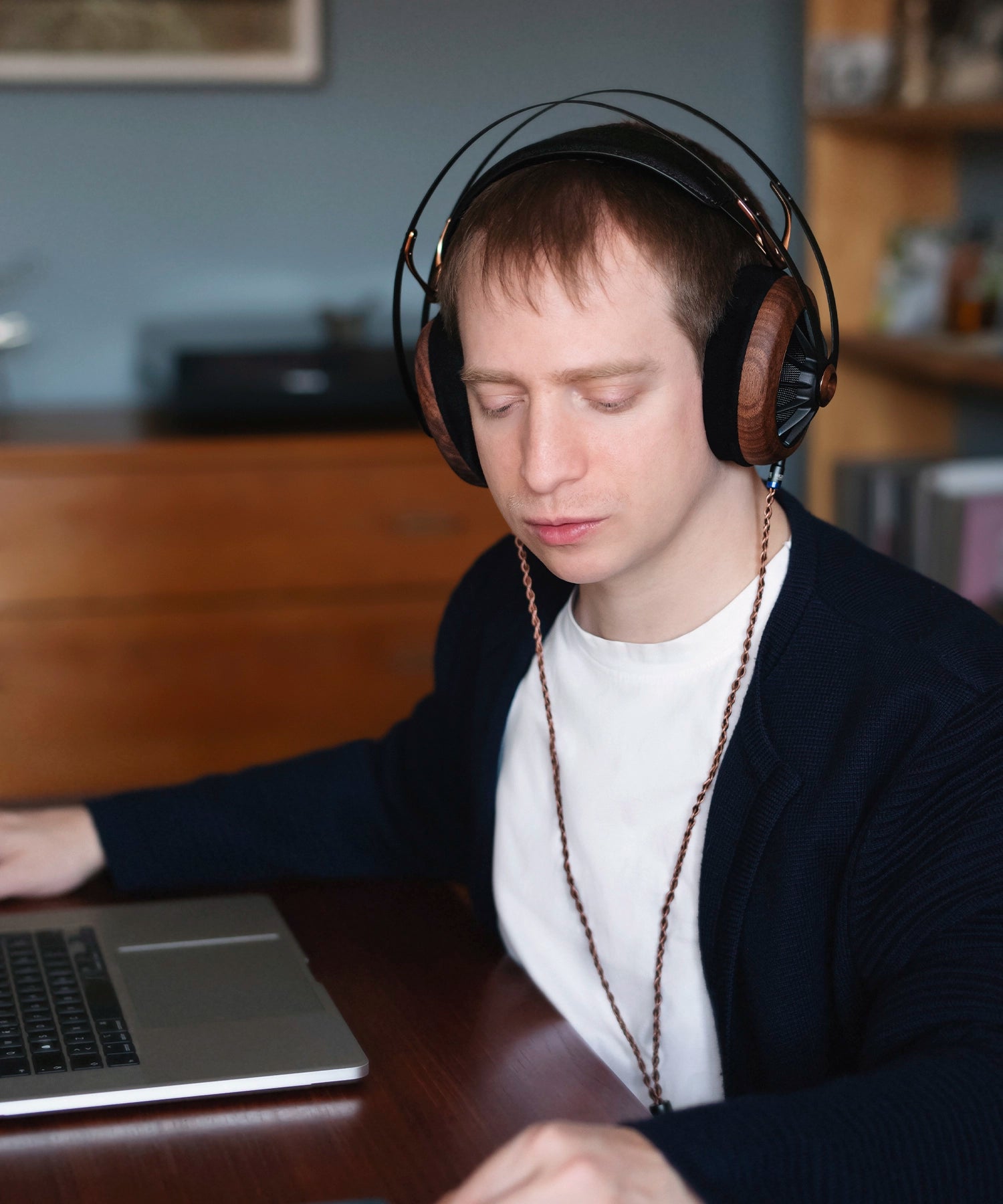 Man sitting at his office desk with a laptop working and listening to music on his Meze Audio 109 PRO wired head phones