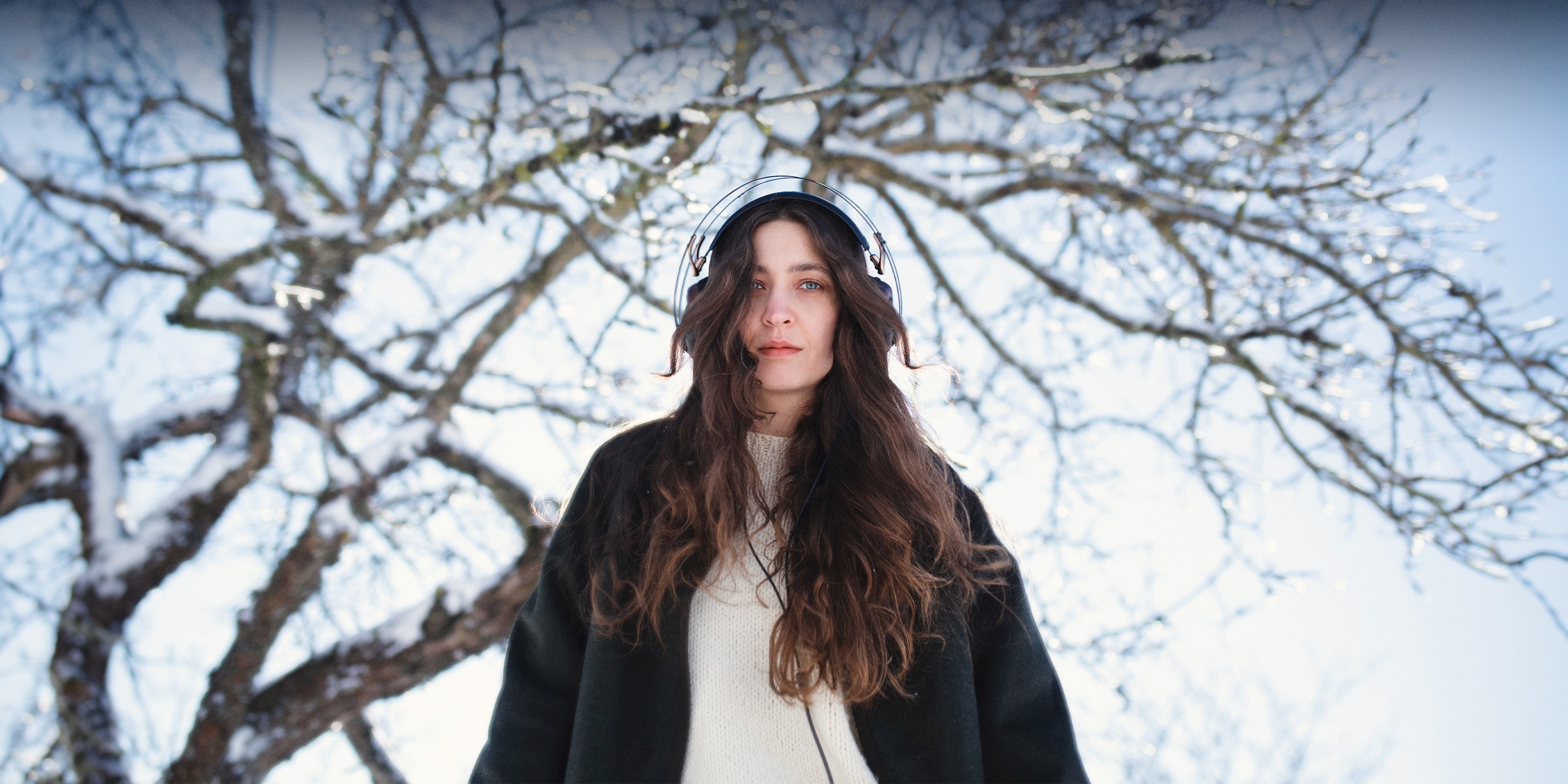 Young woman with long hair on a snowy day listening to music on her Meze Audio 109 PRO wired head phones