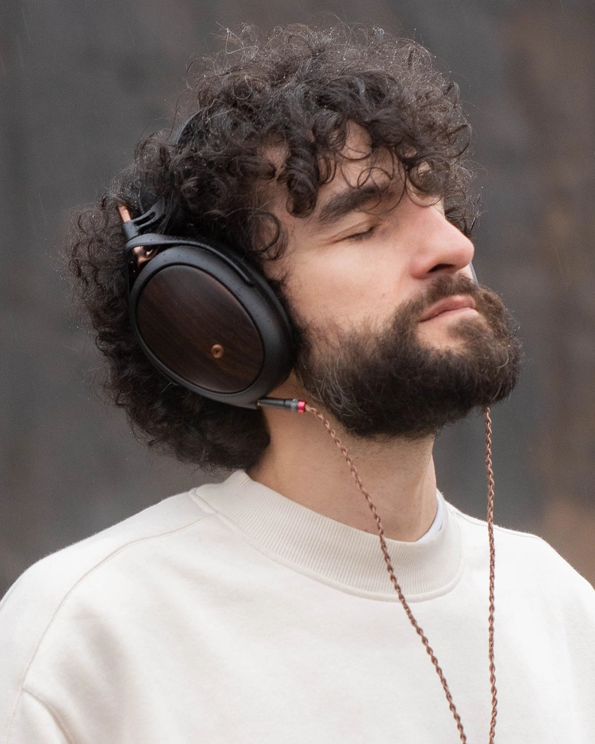 Man listening to Meze Audio Liric second generation premium build closed-back wooden ear cups copper cables outdoor