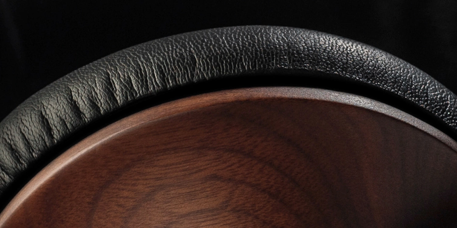 Detailed close-up showing the craftsmanship of the walnut wood ear cups of these closed-back audiophile headphones, emphasizing premium build quality.