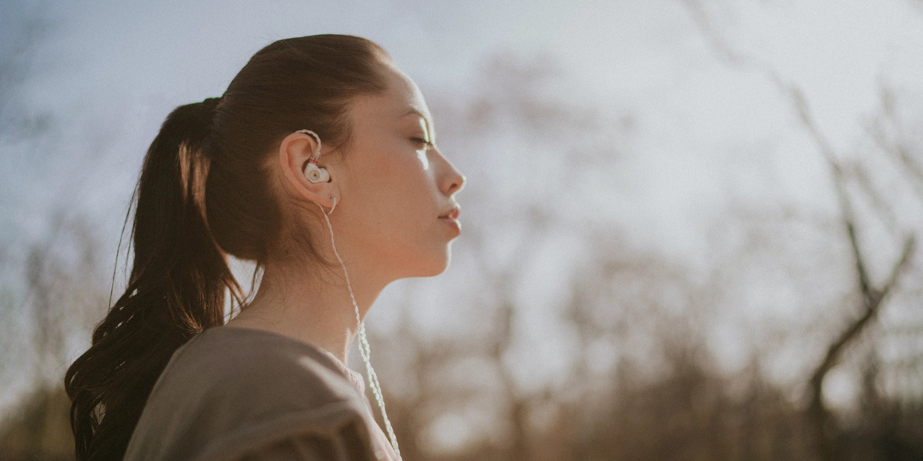 Young woman wearing the Meze Audio Alba best wired earbud headphones while walking in the forest