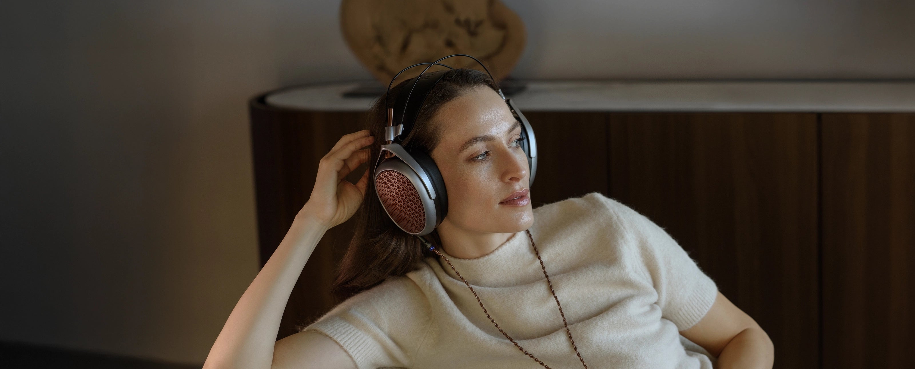 Woman listening to premium Meze Audio headphones POET indoors copper cable